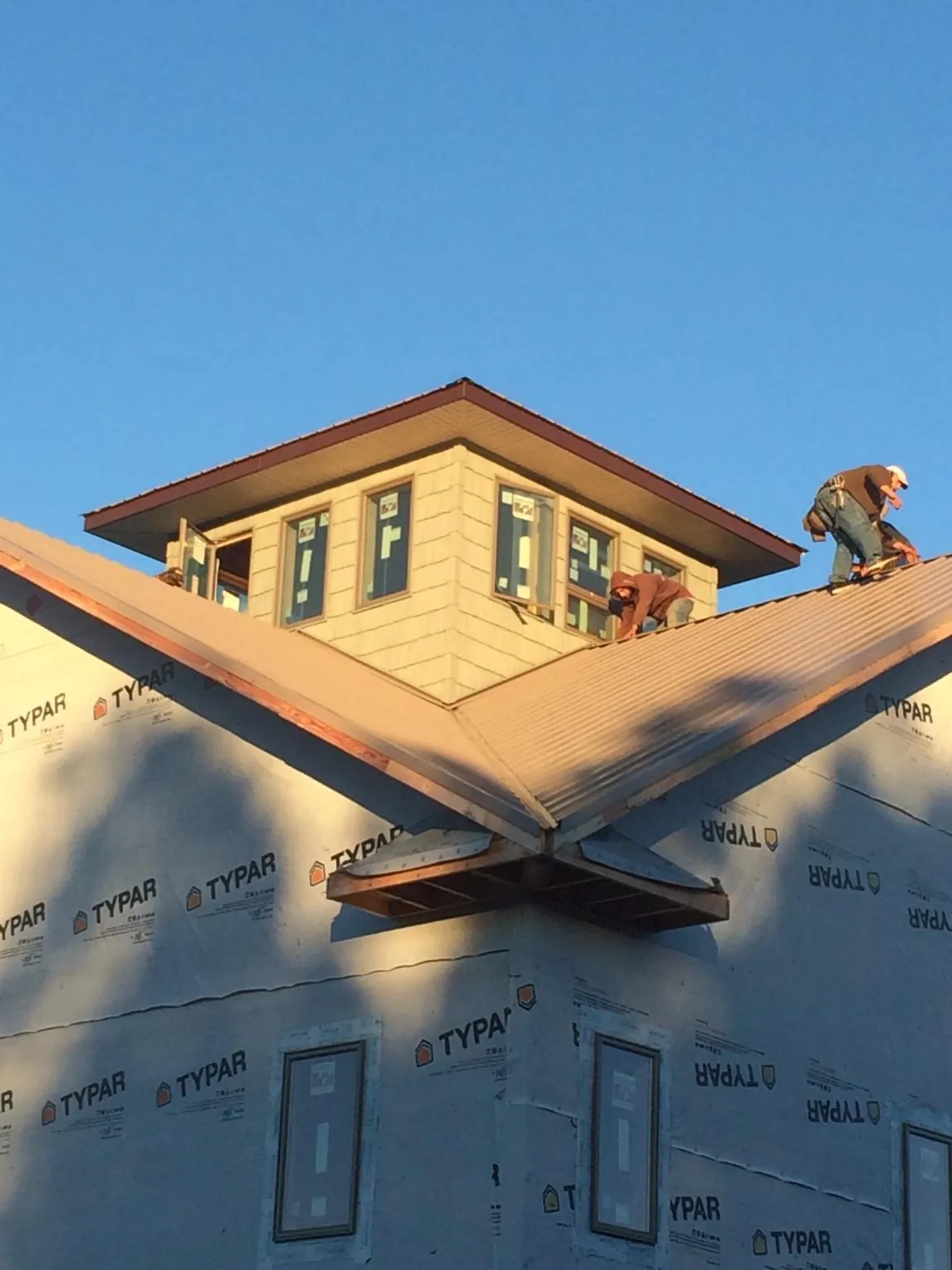 Roofers working around a rooftop cupola on a new metal roof at sunset — Roof Waterproofing in Oneonta by Roofing Brothers